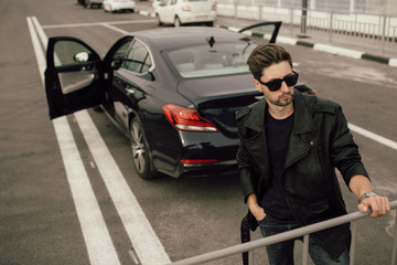 Fototapeta na wymiar young fashionable man in glasses near the car