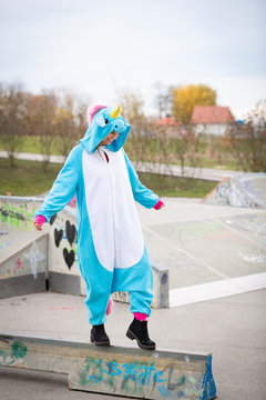 Beautiful Young Woman Wearing Turquoise Unicorn Onesie In Urban Environment