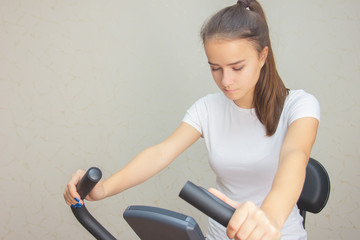 Young girl is engaged on a stationary bike at home