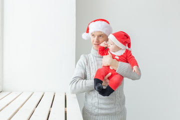 Obraz premium Fatherhood and holidays concept - Father with his baby boy wearing Santa hats celebrating Christmas