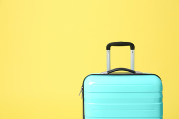 Stylish turquoise suitcase on yellow background. Space for text
