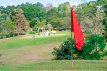 Golf flag on green of golf course on hills on blue sky background