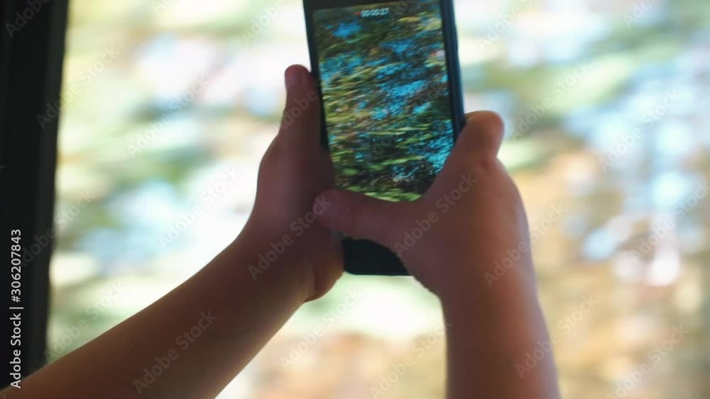 Poster close-up of a smartphone in the hands of a child in a moving train.