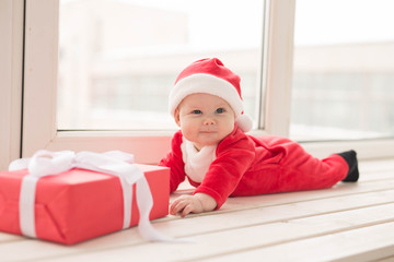 Beautiful little baby celebrates Christmas. New Year's holidays. Baby in a Christmas costume and in santa hat