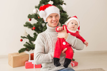 Father with his baby boy wearing Santa hats celebrating Christmas.