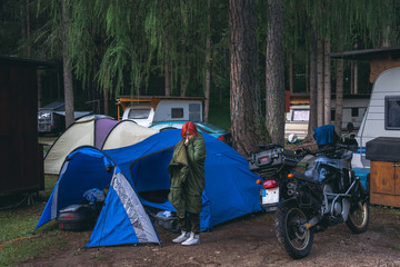 Portet of a girl who did not sleep well at night. Fatigue after a hard road. Feeling unwell in the morning. Sheltered by a warm bedspread, sleeping bag. Campers, tent and motorcycle in the background