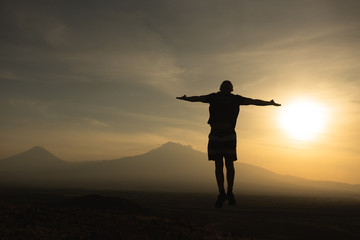 a man travels in Armenia, Yerevan. At sunset, she jumps silhouettes against the backdrop of Mount Ararat. Very beautiful landscape.