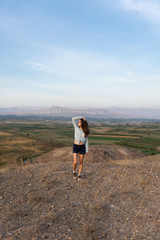 Naklejka na ściany i meble Beautiful and slender Girl travels in Armenia, Yerevan. At sunset, she jump silhouettes against the backdrop of Mount Ararat. Very beautiful landscape