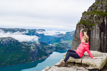 Naklejka premium Girl on Prekestolen or Pulpit Rock in the rain. Norway.