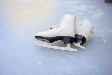 A pair of curly female skates lies on the ice at the rink