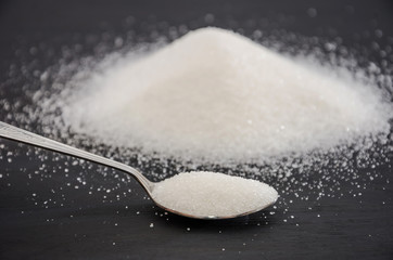 white sugar and spoon on a black background