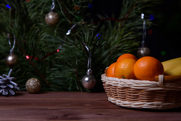 Fototapeta na wymiar Christmas, decoration on a wooden table. Christmas tangerines in a wicker basket, cones and golden Christmas balls