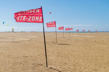 Red flags with warning `danger, kite zone` border Playa Sotavento beach in Fuerteventura, Canary Islands, Spain