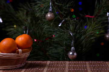 Christmas, decoration on a wooden table. Christmas tangerines in a wicker basket, cones and golden Christmas balls