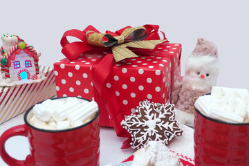 Gingerbread cookies in the shape of a snowflake, red mugs with coffee and marshmallows, gift boxes, toy snowman...