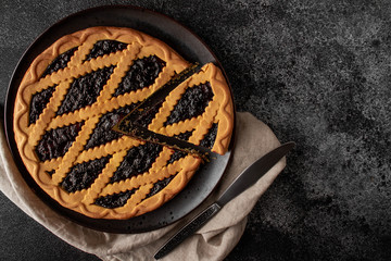 Shortcrust pie with black currant. Top view. Dark key food photo. Pie on a black background. 