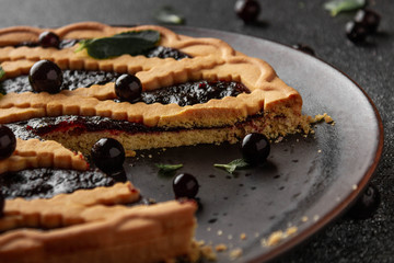 Shortcrust pie with black currant. Top view. Dark key food photo. Pie on a black background. 