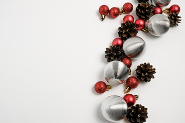 Christmas winter composition. Red and silver balls with pine cones on white background. Top view, flat lay 