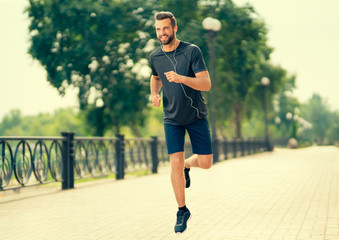 Young happy cheerful smiling handsome bearded man, during morning jogging outdoors. Fitness, sport,...