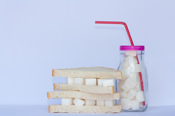 Sandwich with sugar and glass full of sugar cubes .Too much sugar and unhealthy food concept.