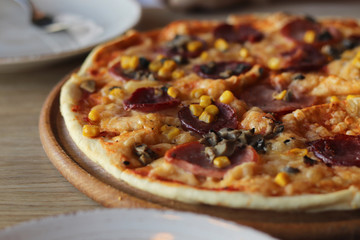 Tasty hot pizza on a wooden plate. Cutlery. Food in cafe