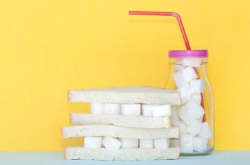 Sandwich with sugar and glass full of sugar cubes .Too much sugar and unhealthy food concept. - obrazy, fototapety, plakaty