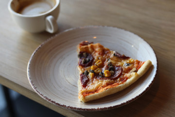 Tasty pizza on a white plate and a cup of coffee. Top view of hot pizza