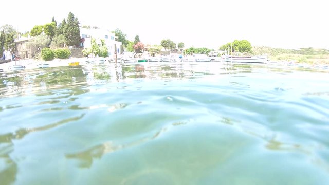 CADAQUES, CATALONIA, SPAIN &ndash; AUGUST 2019 : coastline of the village of Portlligat, Costa Brava, Mediterranean sea, camera moves from underwater to above water surface, panning shot
