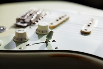 close up of white electric guitar with strings and buttons