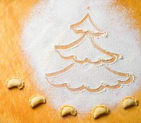 Drawing of a Christmas tree on a cutting Board made of white flour