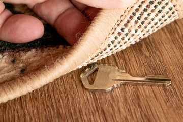 A man raises a key hidden under a mat