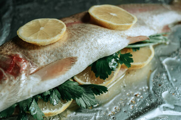 Fresh fish with parsley and lemon on foil prepared for baking