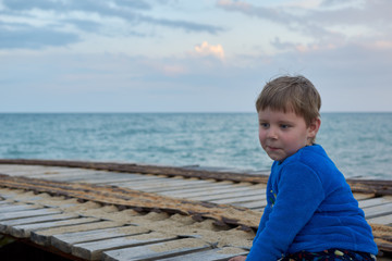 boy with a surprised expression in the evening near the sea