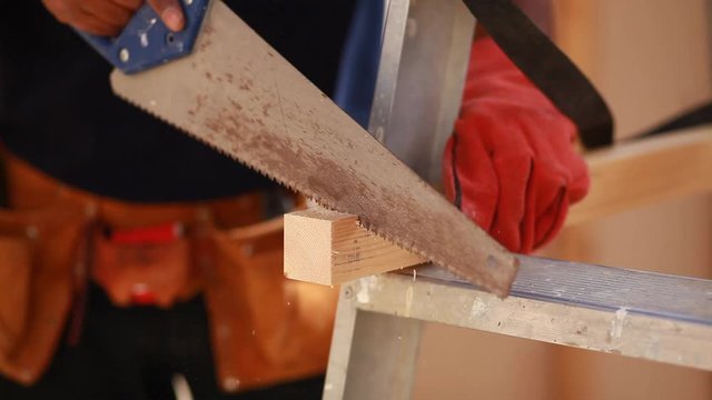 hands of young man working cutting plank with wood handsaw