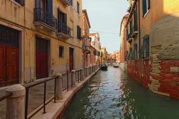 Fototapeta na wymiar Stunning landscape view of street in Venice. Typical street with ancient building, narrow canal with turquoise water. Beautiful cobblestone pathway along the buildings. Venice, Italy