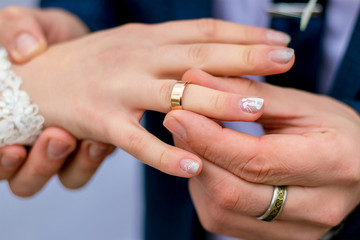 The groom puts a wedding ring on the bride's finger_