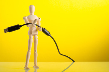 wooden man figure with usb plug on yellow background