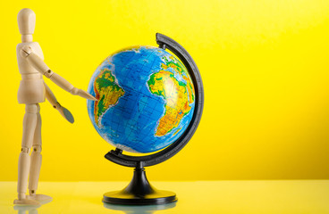 wooden man figure with globe travel on yellow background