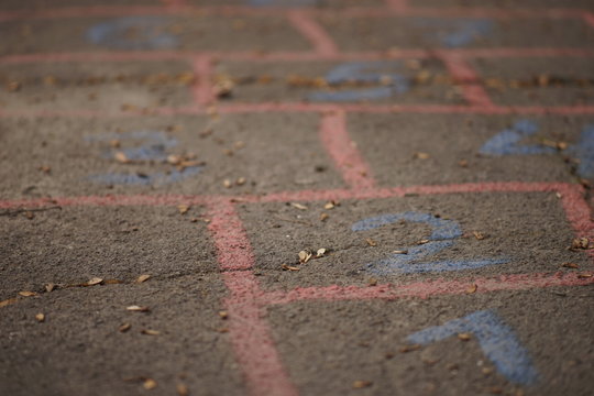 Children's hopscotch game painted on asphalt road.