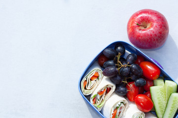 Lunch box with tortilla wraps, fruits and vegetables. Healthy eating concept.