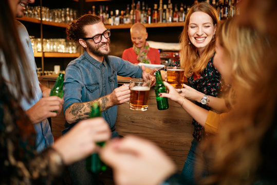 Group of friends drinking beer, chatting and having good time at pub. Night out.