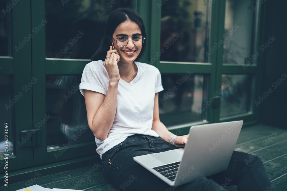 Poster portrait of cheerful hipster student in classic optical eyewear smiling at camera during e learning 