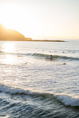 Surfers riding waves on Zurriola Beach in San Sebastian during sunset