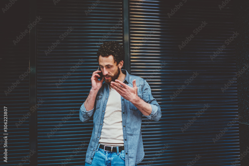 Aufkleber angry bearded young man gesturing hands while solving problem during phone conversation on smartphon