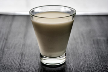 Milk in a glass cup on a wooden background. Photographed close-up in a low key.