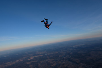 Skydiving. A solo skydiver is in the sunset sky.