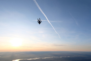 Skydiving. A solo skydiver is in the sunset sky.