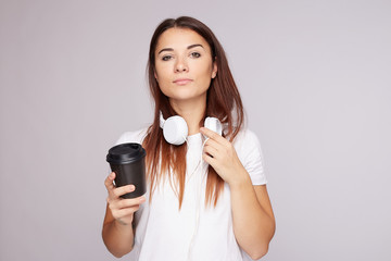 Serious long straight haired female listens audio tracks via headphones during coffee break, has...