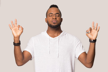 Calm African American man in glasses meditating, breathing, stress relief