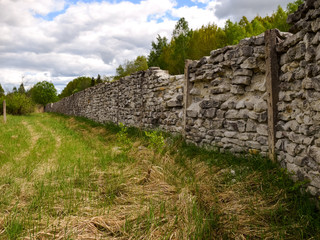 view through a stone fence over a white mountain and green trees